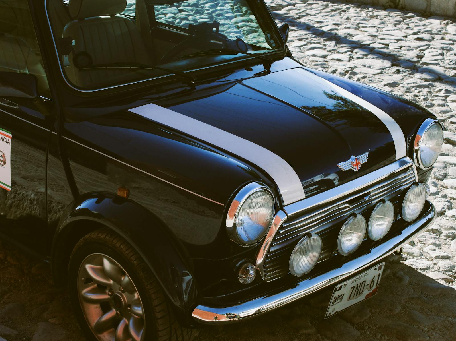 A black mini cooper parked on a cobblestone street