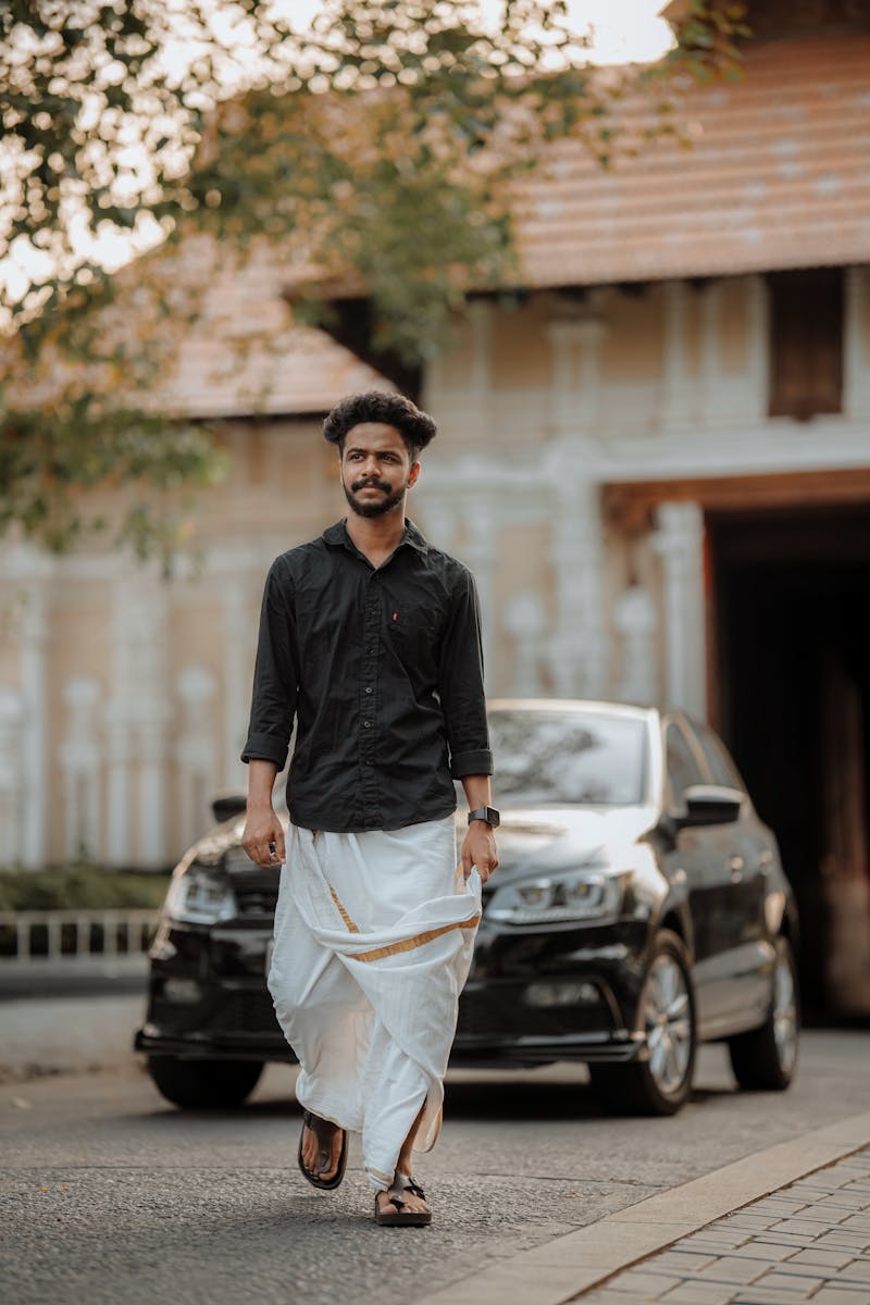 A Man Wearing a Dhoti Walking in front of a Car in City